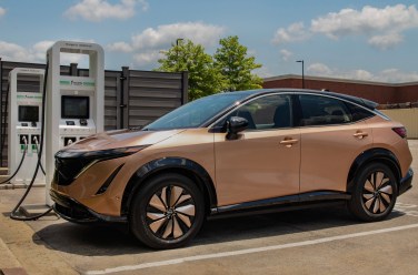 a bronze Nissan ariya suv parked at a charging station