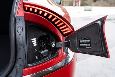 Close-up of a CCS Combo charge port on the rear right side of a red Kia EV6, hatch opened